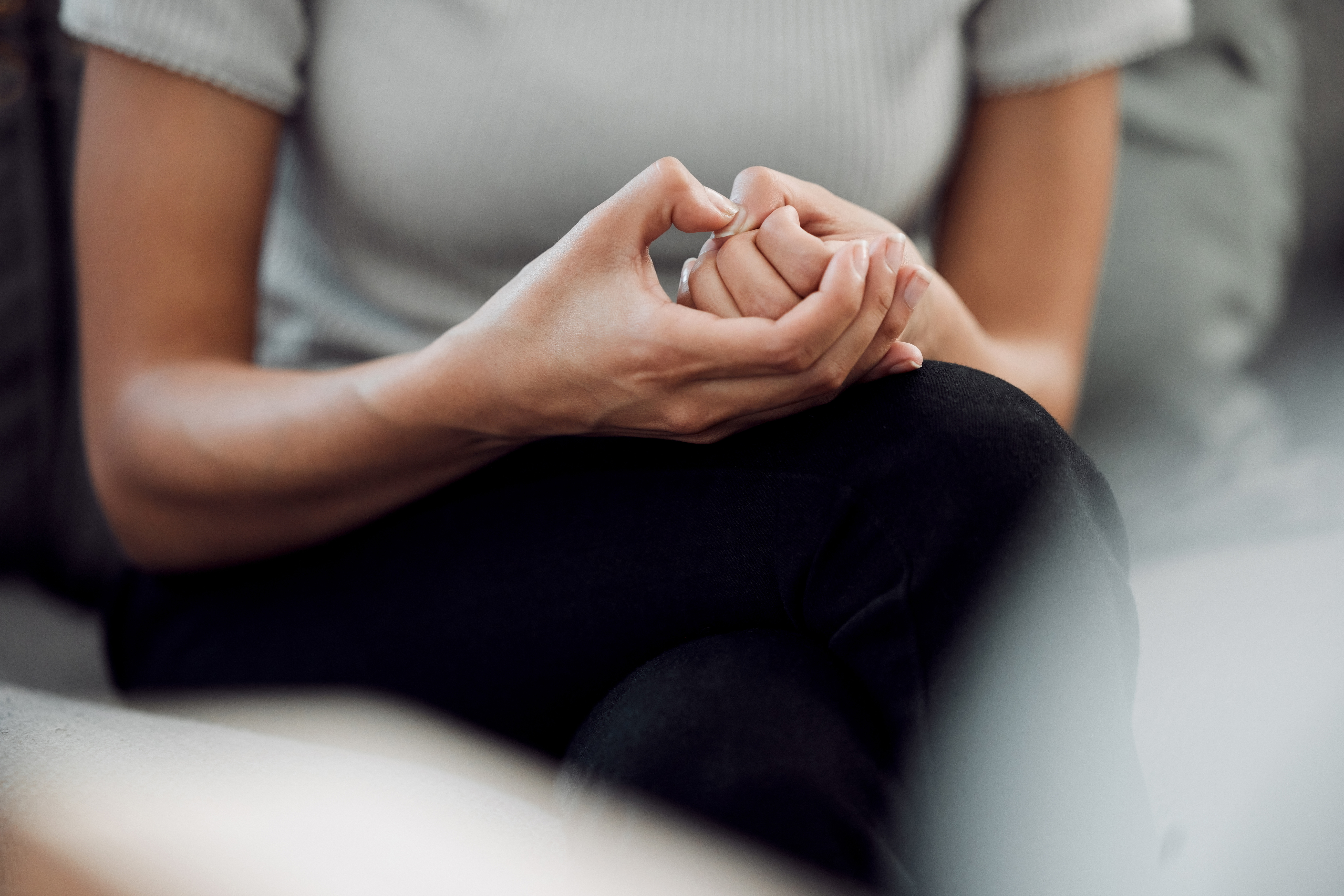 Person sitting with clasped hands